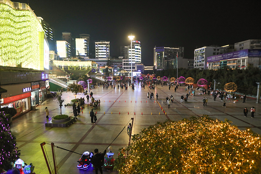 夜晚城市廣場，燈火璀璨，人流如織